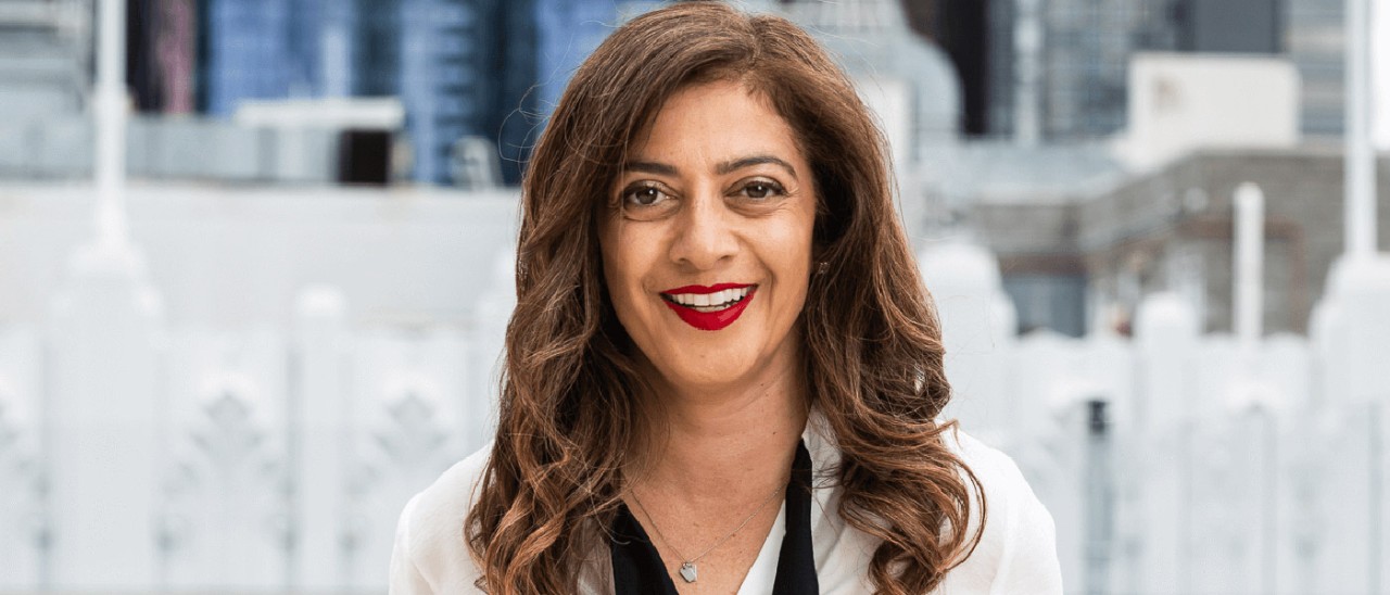 Woman in business clothes smiling on a building's balcony in the city.