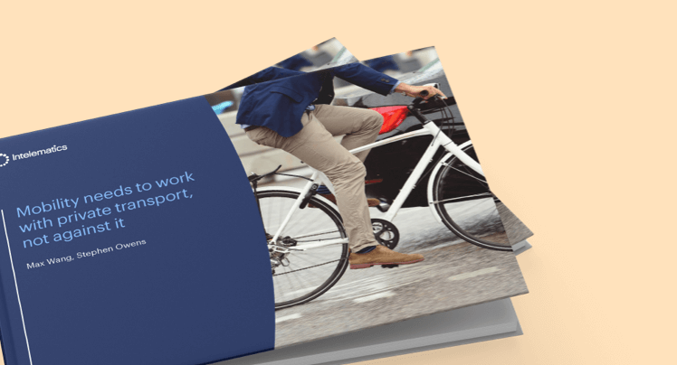 Person in beige pants and blue jacket riding a white bicycle on a wet city street.