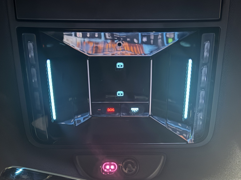 Close-up of a BYD Sealion 8 overhead console showing the red illuminated SOS emergency call (eCall) button, powered by Intelematics